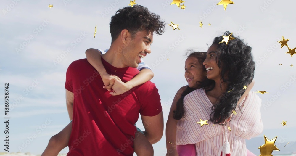 Obraz premium Smiling family standing close together at beach, wearing red T-shirt and pink blouse, gold stars