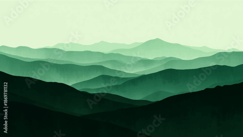 Misty blue mountain landscape at sunrise featuring a forest valley and cloud covered peaks under a glowing horizon