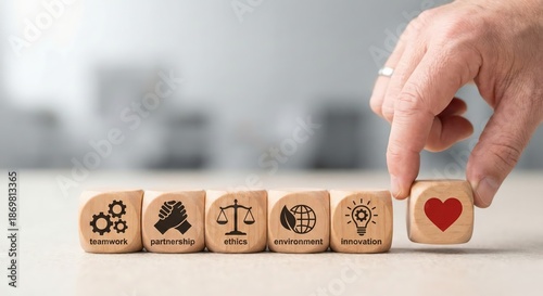Close-up of a Caucasian adult hand placing a wooden block with a human-centric icon next to icons for ethics and sustainability on a light wooden table, high-key corporate business strategy concept.