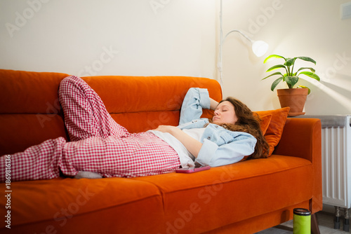 Slika na platnu Caucasian woman resting on a cozy orange couch feeling unwell with toxicosis sym