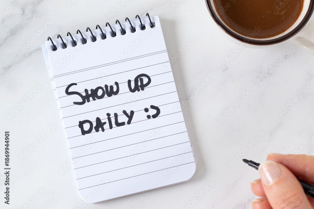 Naklejka premium Show up daily, inspirational handwritten quote in notebook with coffee cup. Top view. The concept of personal growth, motivation, progress, and success.