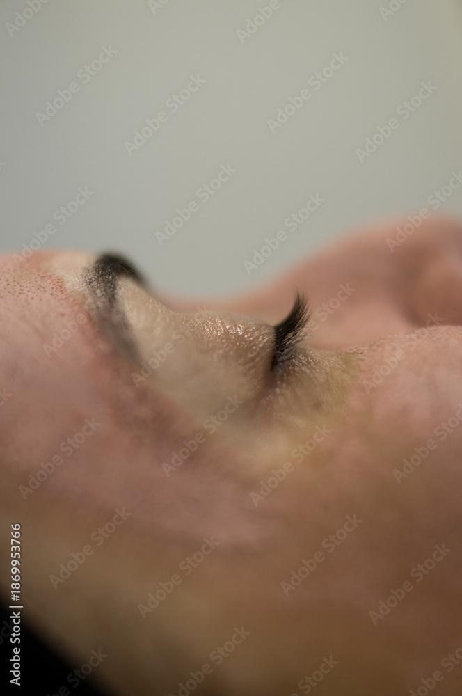 Naklejka premium Side view of a woman with eyes closed, enjoying a relaxing moment with a pink face mask. Soft focus background, emphasizing the feeling of peace and tranquility.