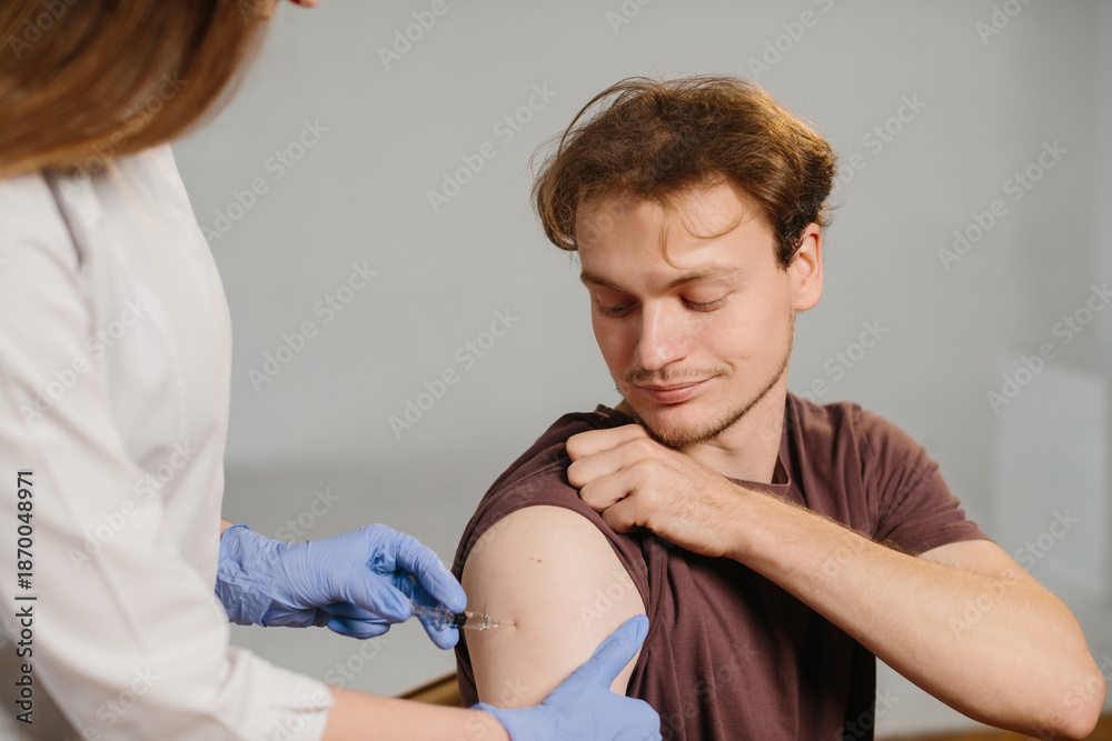 Fototapeta premium Young man receiving vaccination from medical professional