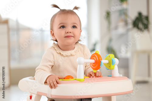 Cute little baby girl in walker at home