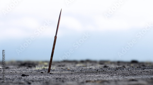 Rusty Spear Piercing an Empty Landscape Under a Cloudy Sky, Evoking a Sense of Isolation and Mystery in Nature’s Vastness