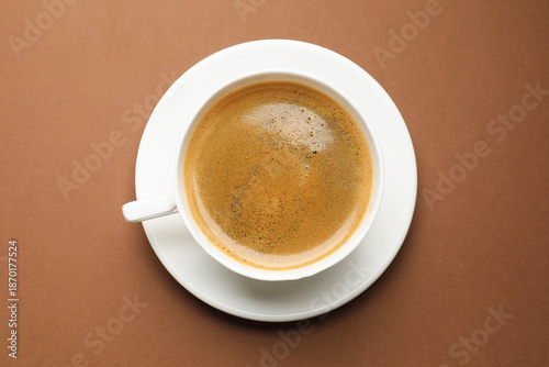 Aromatic coffee in cup on brown background, top view