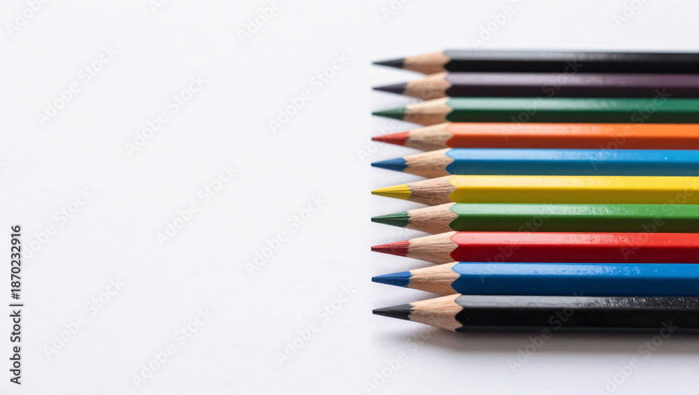 Fototapeta premium A neat row of sharpened colored pencils displaying a vibrant spectrum of colors is arranged against a clean white background, creating a minimalist and artistic composition.