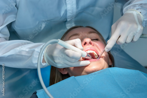 Photos Dentist performing professional dental cleaning using scaler and suction during oral hygiene procedure