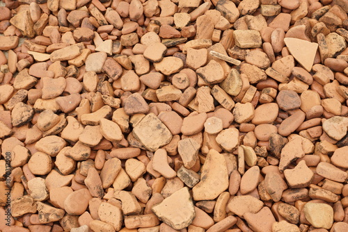 Natural stone gravel texture with small irregular rocks in warm earth tones, forming a rough surface background suitable for construction, landscaping, geology, and material design concepts.