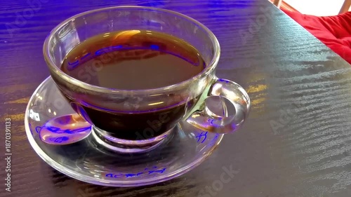Glass cup of americano black coffee with spoon and plate.