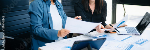 Asian senior and middle aged businesswomen reviewing documents and reports in office. Professional teamwork, mentorship, business collaboration