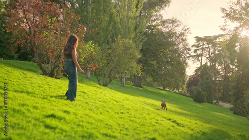 Woman playing fetch with her dog in a sunny park