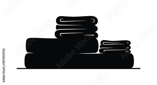 A neatly stacked pile of folded towels presented in a dark striking silhouette