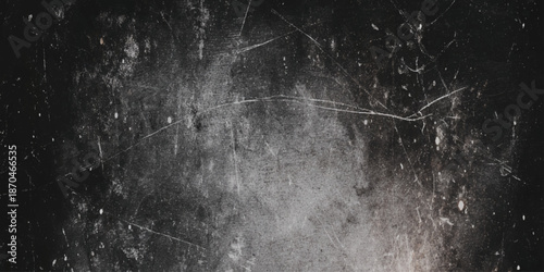 A grayscale image featuring a darkly textured surface with numerous scratches cracks and subtle light variations