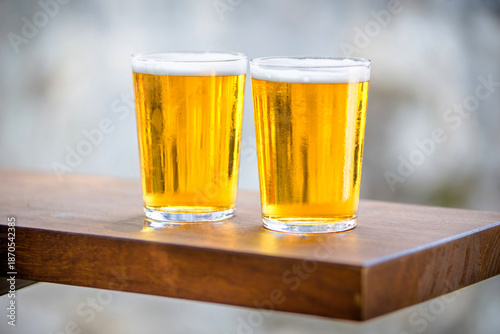 Two glasses of beer are on the bar
