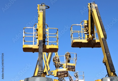 Photos Rear and side view of  cherry picker buckets with blue sky on background