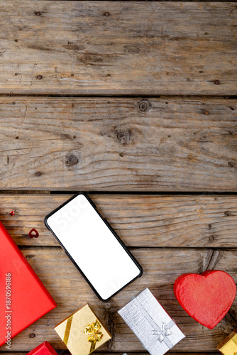 Overhead view of blank screen on smart phone by valentine gifts on table, copy space