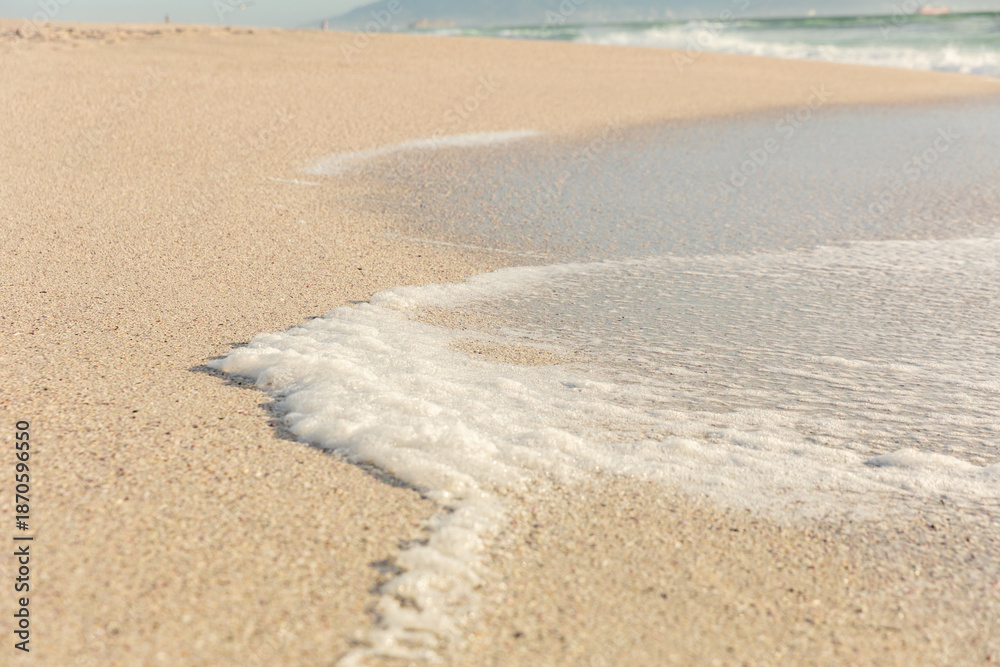 Obraz premium High angle view of white sea wave foam on shore at sunny beach