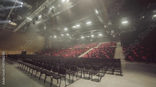 Light fills concert hall highlighting amount of red seats and stage design. Silence creates calm atmosphere before musical performance