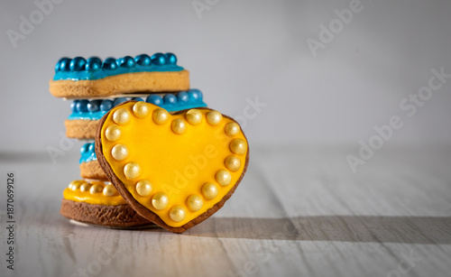 Valentine’s day composition with cookies in shape of hearts decorated by yellow and blue icing and sprinkles on towel embroidered with Ukrainian ornament
