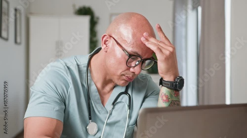 Focused Male Doctor Working on Laptop, Demonstrating Thoughtful Concentration and Medical Professionalism