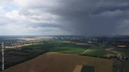 Aerial view of agricultural fields under a dramatic sky. This footage is perfect for projects related to agriculture, weather, or rural landscapes.