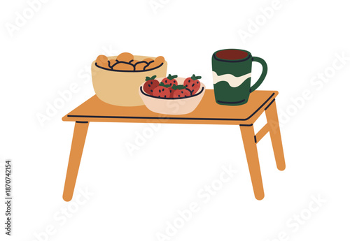 Table with snacks and drinks. Coffee mug, strawberries and pastries in bowls....