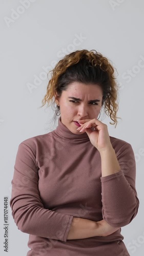 Vertical video of a pensive woman thinking hard, getting stressed, and then having a brilliant idea. Isolated on a white background.