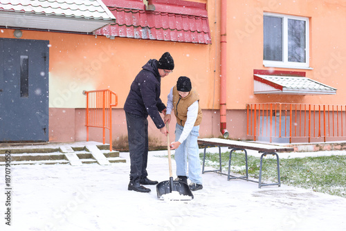 Картината върху платно Two young boys shoveling snow outside a building