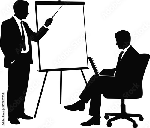 Two men in suits one presenting at a flip chart and the other sitting at a desk with a laptop easel