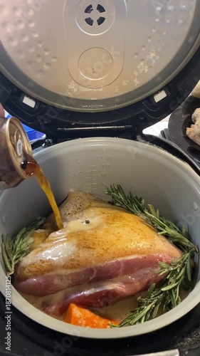 Pork knuckle with rosemary and orange slices, seasoned by hand with amber beer from a jar, cook in an open slow cooker with warm kitchen lighting. Perfect for cooking blogs, recipe apps, or cooking