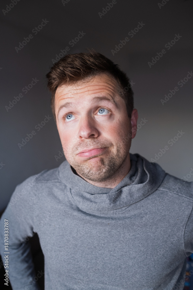 Fototapeta premium Uncertain male person looking up with hesitation, thinking or feeling skeptical.