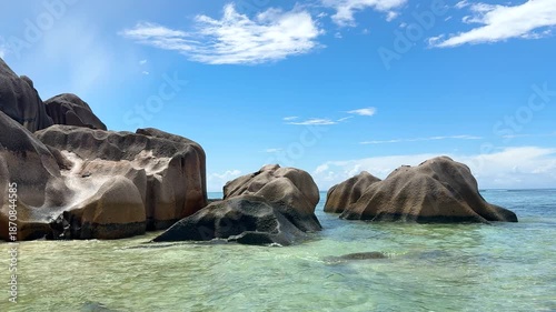 Explore rocky beach with clear water and green cliffs during sunny day