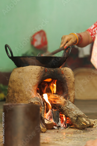 Indian Rural Woman Cooking on Traditional Mud Chulha Stove with Vibrant Flames and Wok