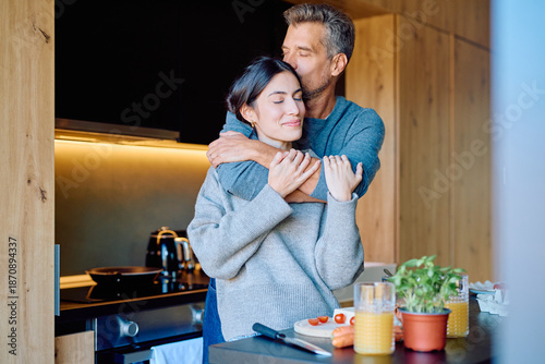 Fotografija Happy couple sharing an intimate moment in their modern kitchen, the man kissing
