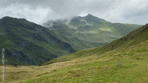 Green Alpine slopes and majestic mountains covered in clouds in the beautiful Austrian landscape of Koenigsleiten
