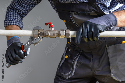 Plumber using a red wrench to repair a water pipe. Repair water pipe,  leaking pipe with water flowing out.