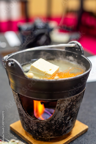 Traditional Japanese hot pot Nabemono with tofu in a steaming iron pot over a stove with fire. Authentic Asian cuisine food photography for restaurant menu and healthy dining lifestyle.