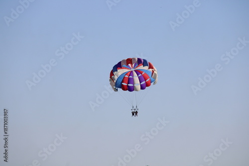 Flying on a multicolored paraglider in the blue sky