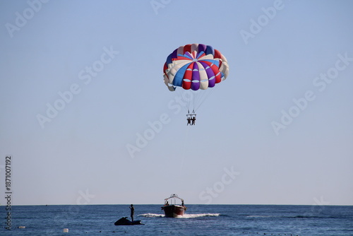 Flying on a multicolored paraglider in the blue sky