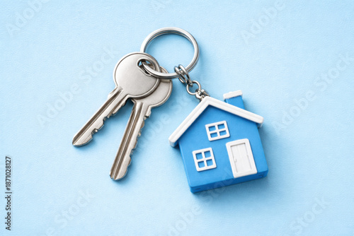 House keys with a small blue house keyring on a bright blue background. Concept of real estate, home ownership, new beginning. Mortgage, purchase of real estate, investment, new apartment, rent, sale.