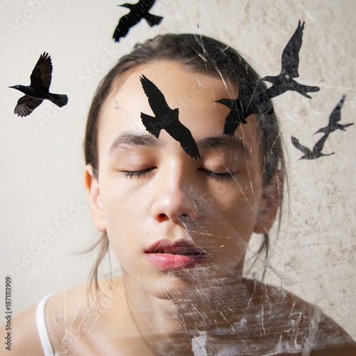 A thoughtful portrait of a person with eyes closed, surrounded by flying black bird silhouettes, enhanced with a cracked texture overlay. Evokes introspection, freedom, and dreams.
