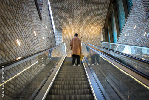 Foto A view of a person in a tan overcoat ascending a modern escalator within the Westgate Shopping Centre in Oxford