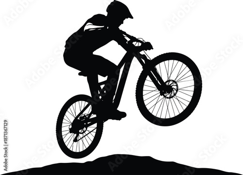 Silhouette of an extreme mountain biker wearing a helmet performing a dynamic jump or trick high above the ground on a rugged trail element during an intense outdoor sport activity