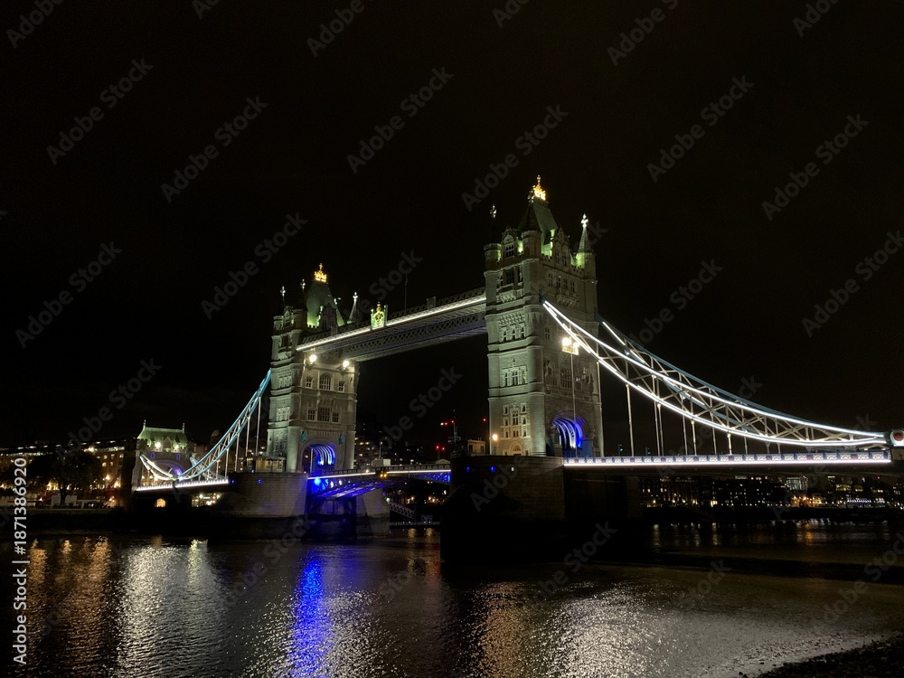 Obraz premium LONDON, UK, October 22, 2019 London Tower Bridge lit at night with reflections on the River Thames, dark sky and city lights in the background.