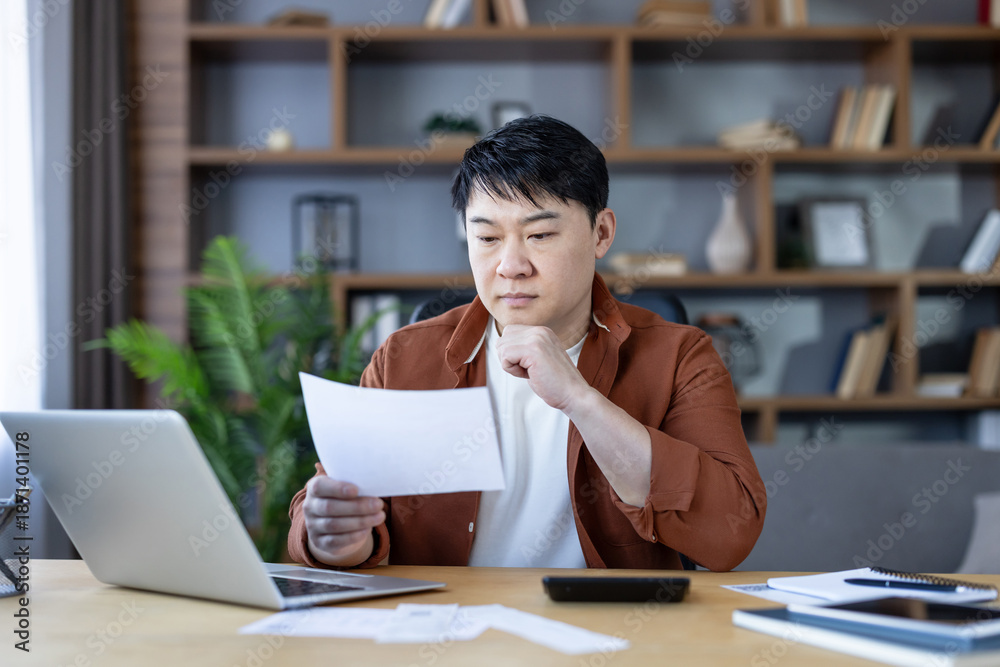 Fototapeta premium Man checking bills and preparing taxes at his home office, analyzing financial documents and using a laptop and calculator for budgeting and debt management