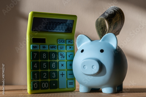 Obraz na plátně Blue piggy bank with a US $1 bill and a calculator