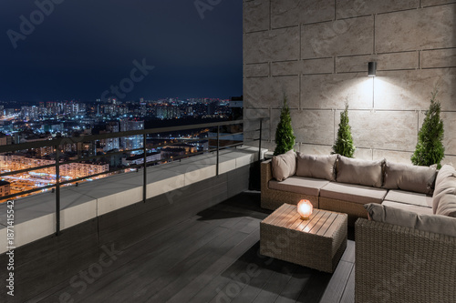 Modern terrace overlooking city lights at night. Cozy outdoor space with candles and urban panorama, luxury lifestyle and relaxation concept.