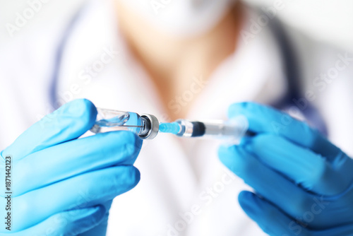 Fotografía Nurse taking vaccine from vial with syringe on light background, closeup