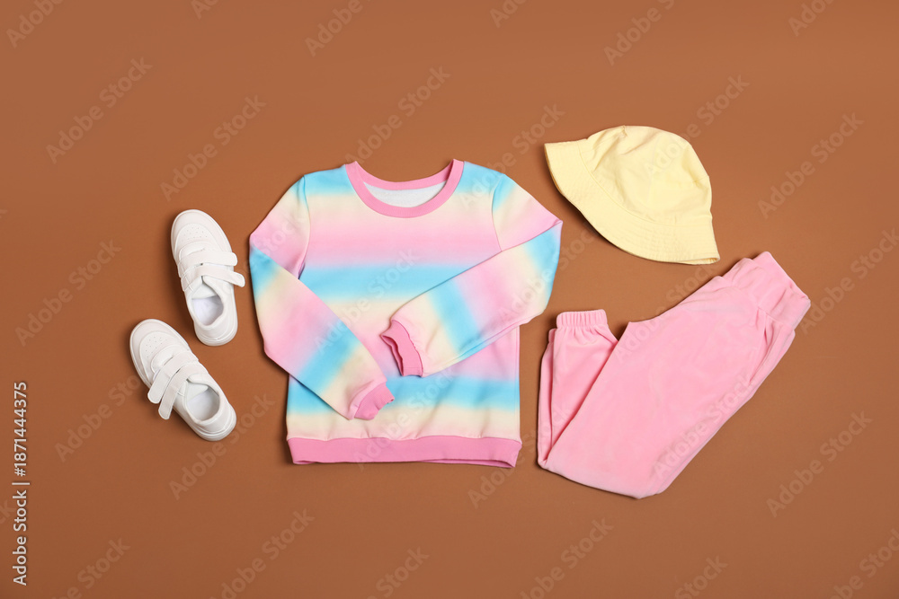 Fototapeta premium Stylish child clothes and shoes on brown background, flat lay